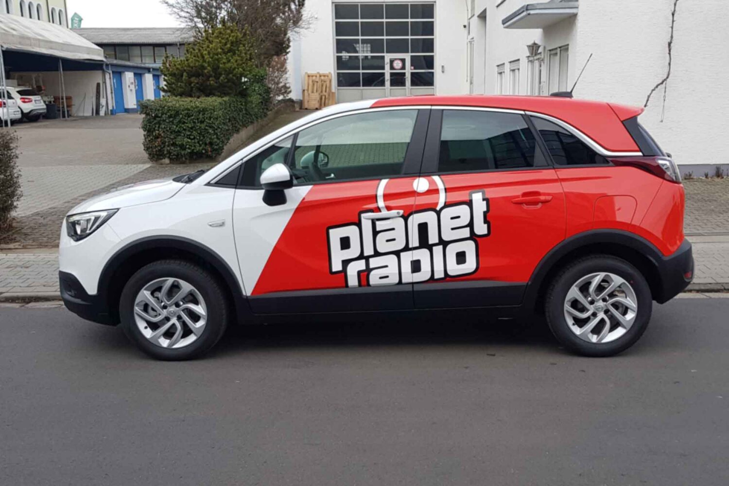 Vollverklebung-Planet Fahrzeugbeschriftung für Planet Radi Vollverklebung in Rot mit Plotts Auto vor unserer Halle in Dietzenbach